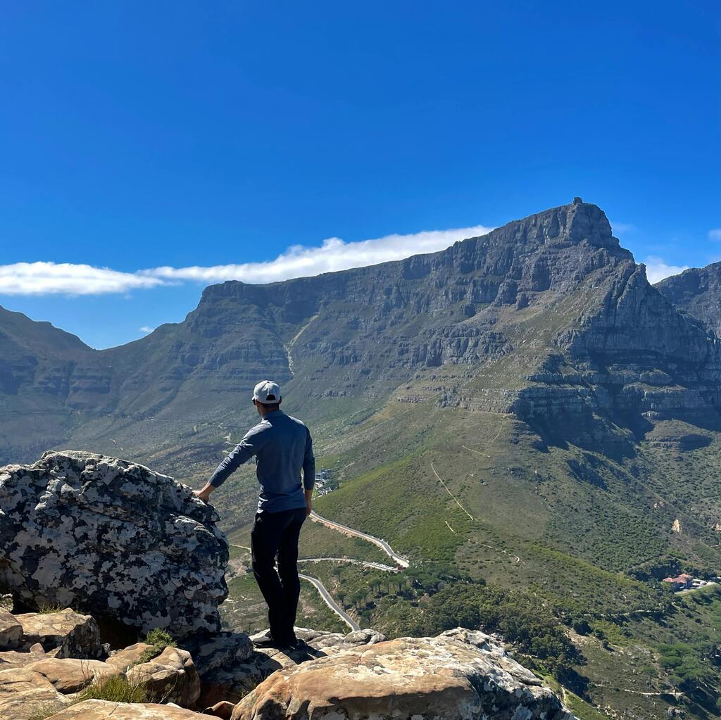 A hiker atop a rocky outcrop gazing at Table Mountain.