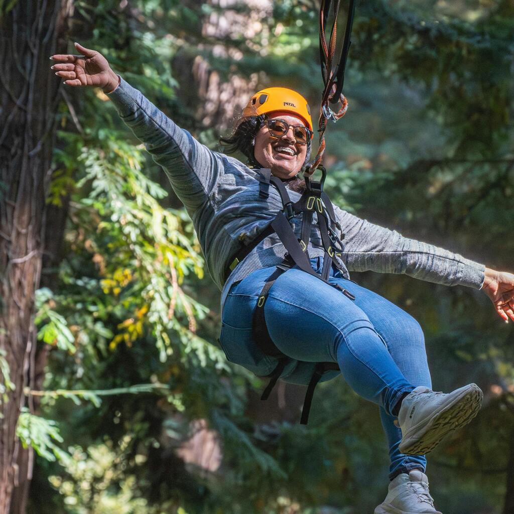 A swoman ziplining through a lush forest.