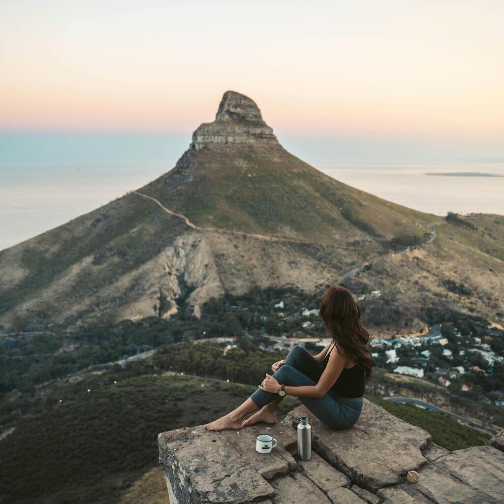 Table Mountain covered in clouds with the city beneath it and red and white flowers in the forefront.