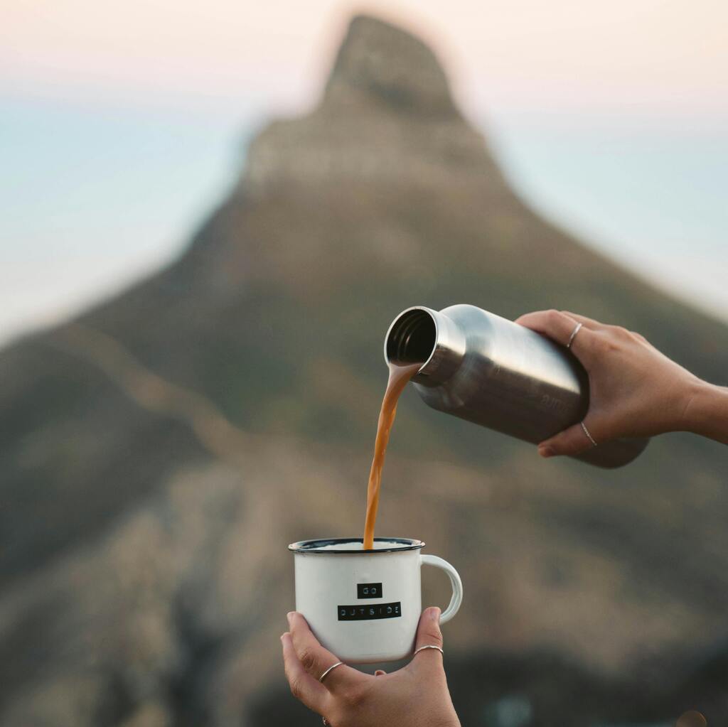 Coffee being poured from a flask into a cup with a Lions Head Mountain backdrop.