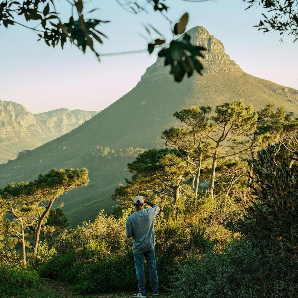 A man standing on a hiking trail admiring the view of Lion's Head in Cape Town. 