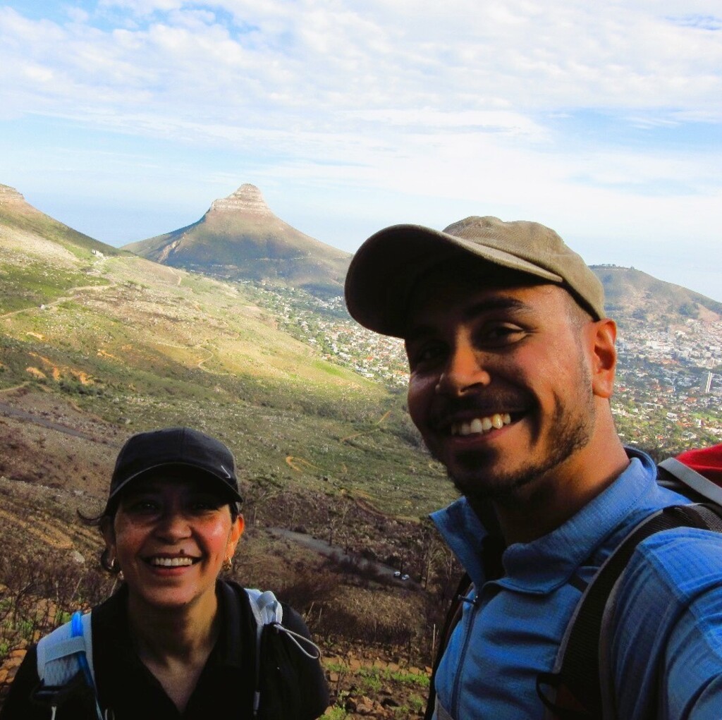 A man and woman hiking with Lion's Head in the background.