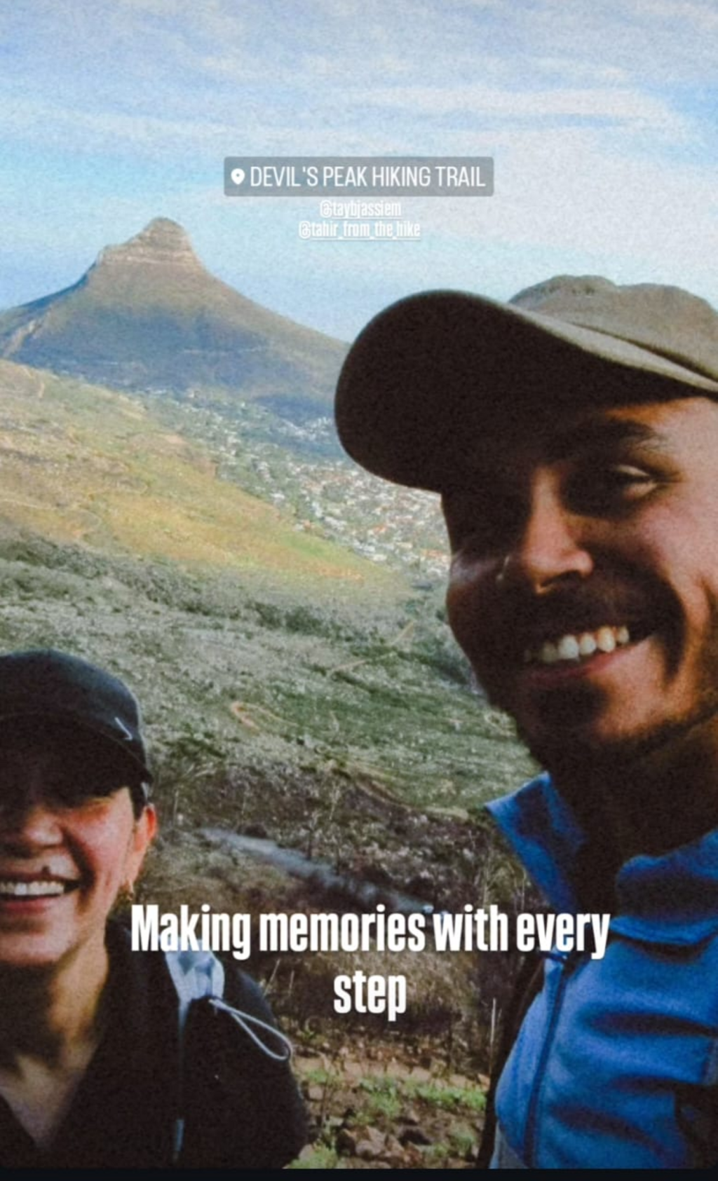 A man and woman smiling at the camera with Lion's Head mountain in the background.