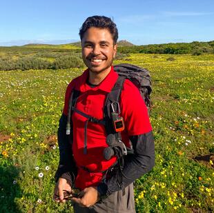 A man standing in a field of wildflowers.